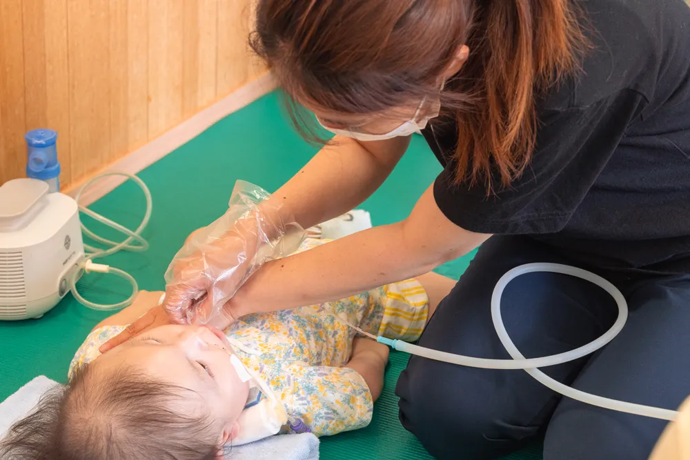 看護師が気管切開のあるお子さんの気管内吸引を行っている様子。